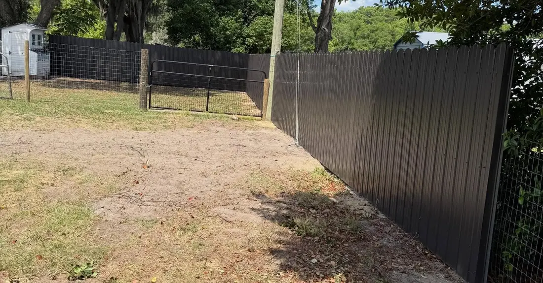 Dark privacy fence transitioning to a farm gate