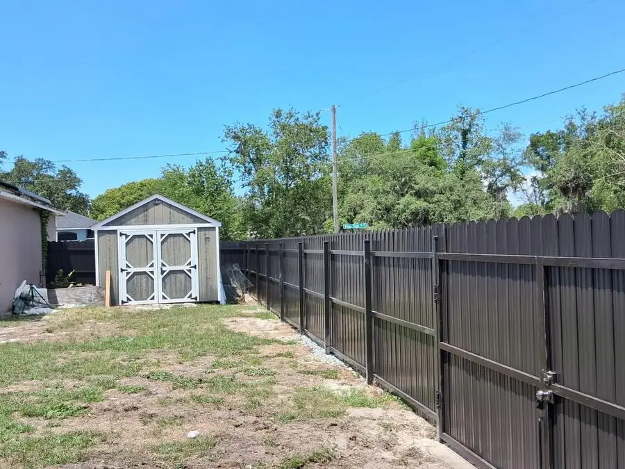 Fence company Kissimmee, FL β dark privacy fence with gate opening to a spacious backyard