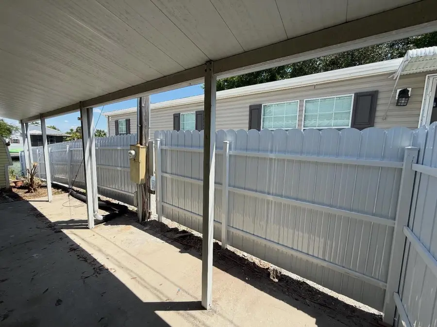 Fence company Daytona Beach, FL β white vinyl picket fence beside a covered carport