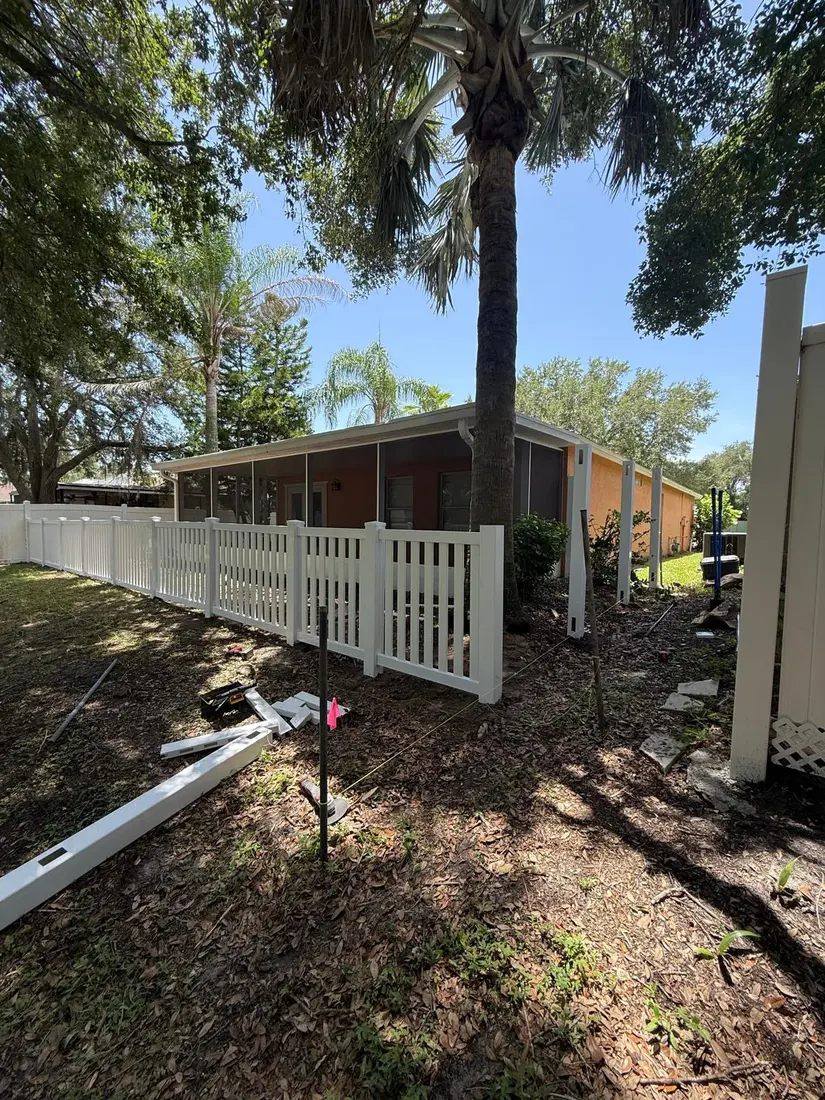 White vinyl picket fence and gate installed beside a screened porch